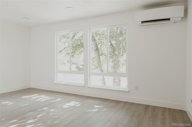 spare room with an AC wall unit and light wood-type flooring