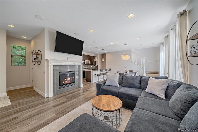 21392 E Stroll Ave, Parker, CO 80138 - living room featuring stairs, light wood finished floors, recessed lighting, and a tiled fireplace