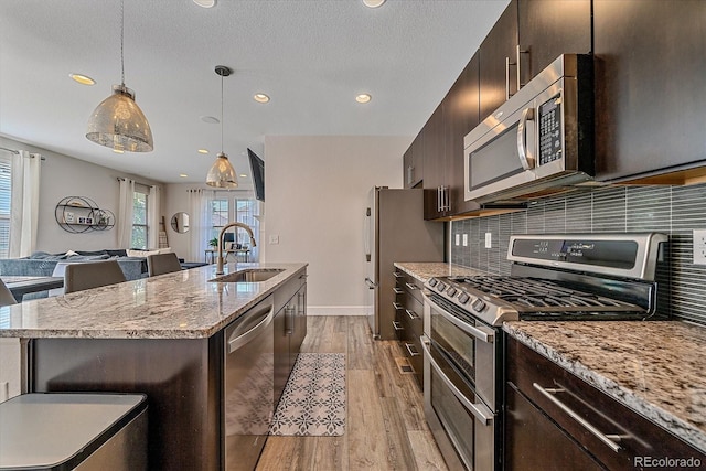 21392 E Stroll Ave, Parker, CO 80138 - kitchen featuring appliances with stainless steel finishes, a center island with sink, light wood-style flooring, recessed lighting, and decorative backsplash