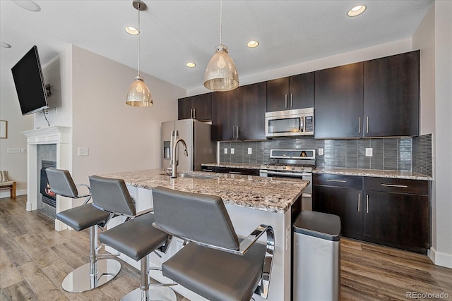 21392 E Stroll Ave, Parker, CO 80138 - kitchen featuring appliances with stainless steel finishes, light wood-type flooring, a breakfast bar, decorative backsplash, and recessed lighting