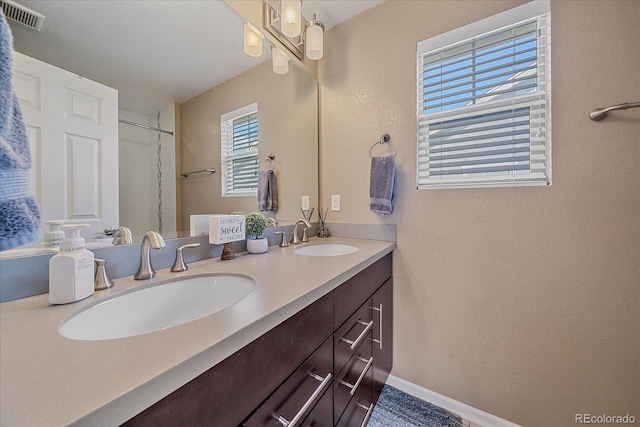 21392 E Stroll Ave, Parker, CO 80138 - bathroom featuring double vanity, a shower, and a textured wall