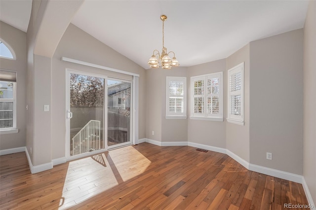 spare room featuring hardwood / wood-style floors, an inviting chandelier, and lofted ceiling