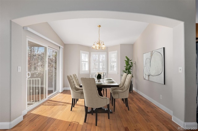 dining room featuring light hardwood / wood-style flooring, a chandelier, and vaulted ceiling