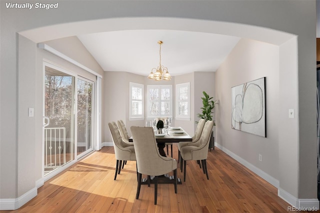 dining room featuring a chandelier, hardwood / wood-style floors, and vaulted ceiling