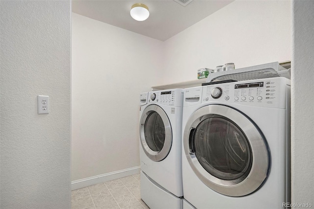 laundry area with washer and dryer and light tile patterned floors