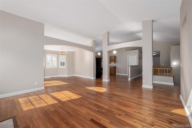 unfurnished living room with dark wood-type flooring and a chandelier