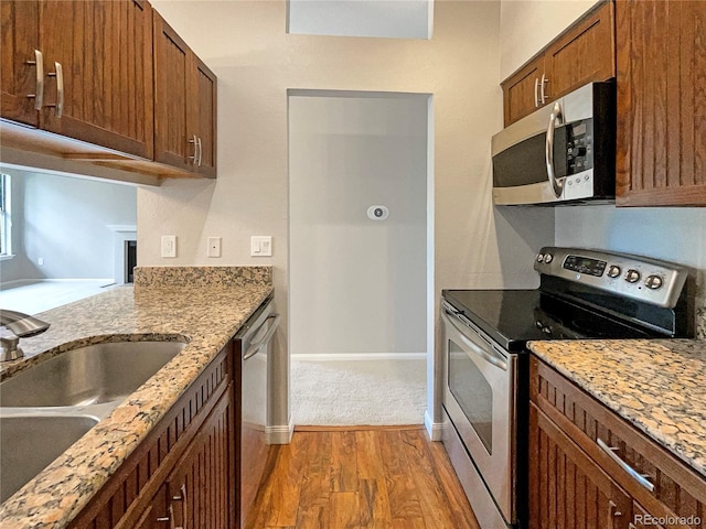 kitchen featuring hardwood / wood-style flooring, appliances with stainless steel finishes, sink, and light stone counters