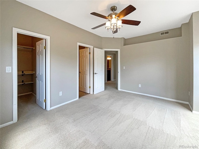 unfurnished bedroom featuring ceiling fan, light colored carpet, and a walk in closet