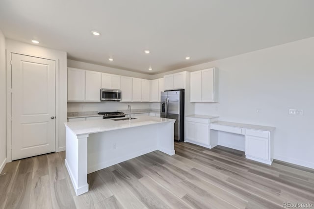 kitchen featuring sink, light hardwood / wood-style flooring, appliances with stainless steel finishes, an island with sink, and white cabinets