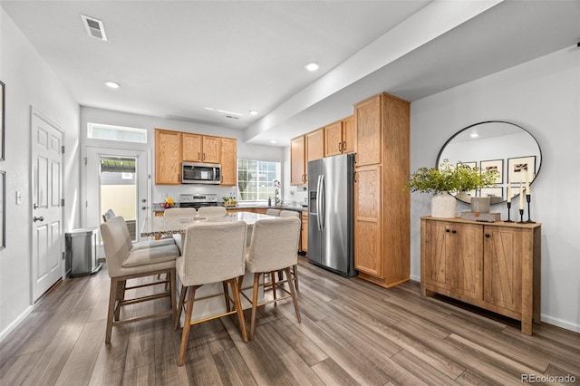 4060 N Rome St, Aurora, CO 80019 - kitchen featuring appliances with stainless steel finishes, dark wood-type flooring, a center island, light stone countertops, and a breakfast bar area