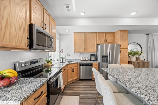 4060 N Rome St, Aurora, CO 80019 - kitchen with appliances with stainless steel finishes, a sink, a kitchen breakfast bar, light stone countertops, and dark wood-type flooring