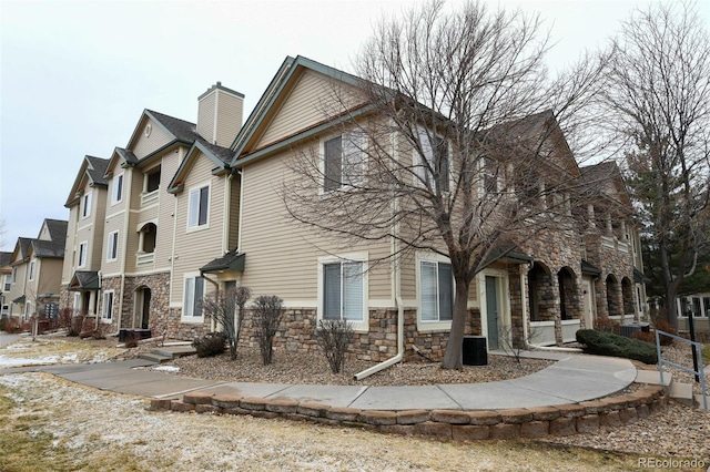 view of front of home with a residential view, stone siding, and a chimney