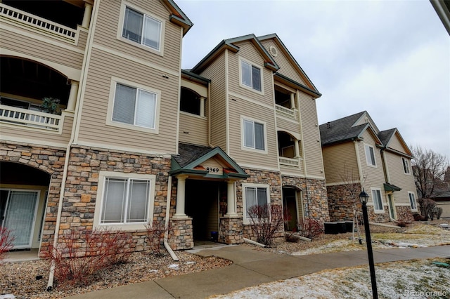 view of property with stone siding and a balcony