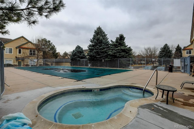 community pool with a patio area, a community hot tub, and fence