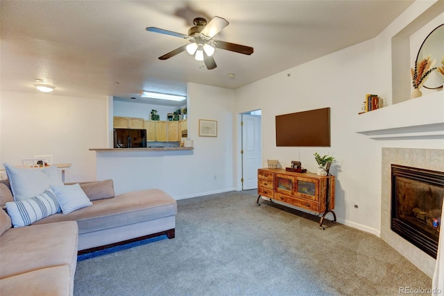 living room featuring light carpet, a fireplace, baseboards, and ceiling fan