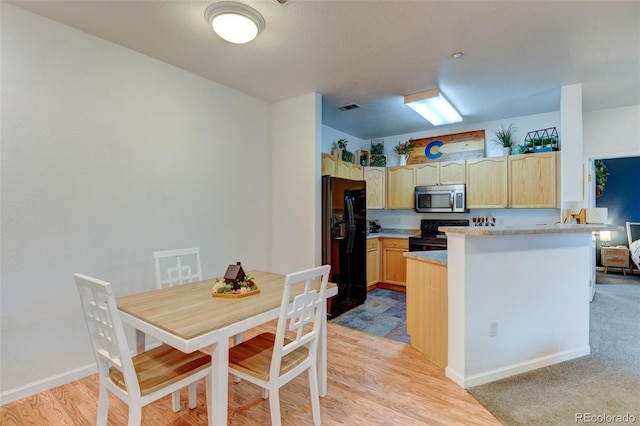 kitchen featuring visible vents, light brown cabinets, light countertops, a peninsula, and black appliances