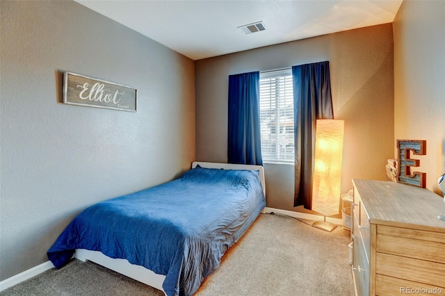 bedroom featuring light colored carpet, visible vents, a textured wall, and baseboards