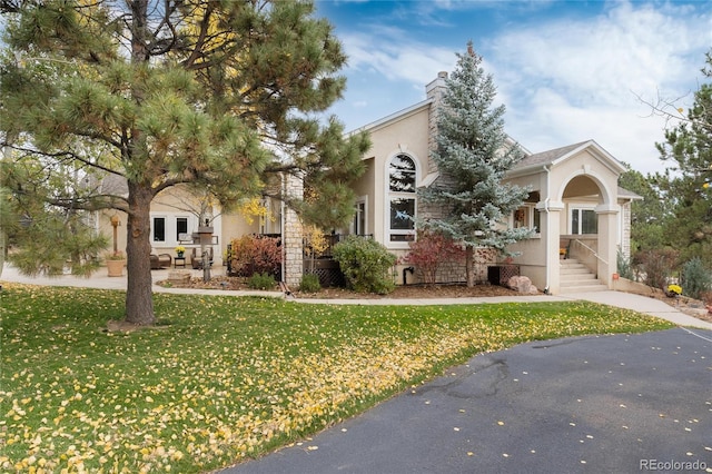 view of front of property featuring a front lawn, a chimney, and stucco siding