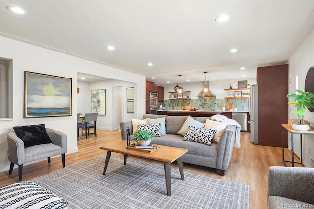 living room featuring recessed lighting, baseboards, and light wood finished floors