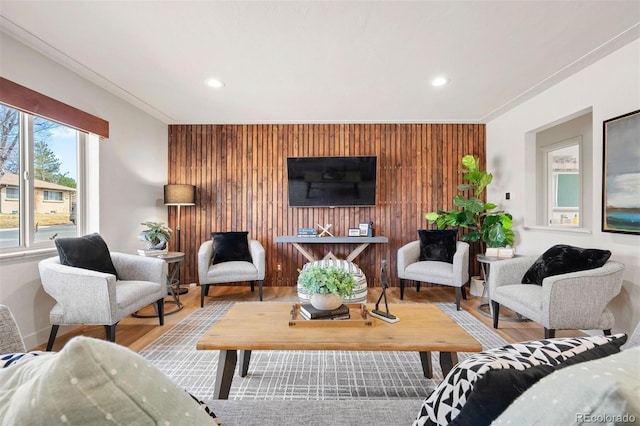 living room featuring an accent wall, wooden walls, recessed lighting, and wood finished floors