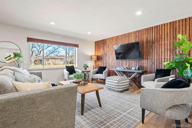 living room with wooden walls, recessed lighting, and wood finished floors