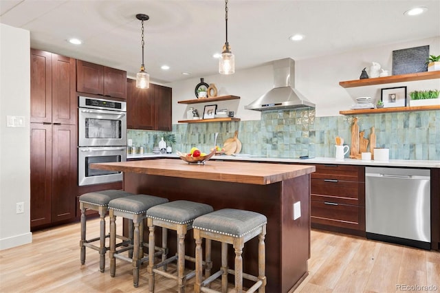 kitchen with a kitchen bar, open shelves, wood counters, appliances with stainless steel finishes, and wall chimney range hood