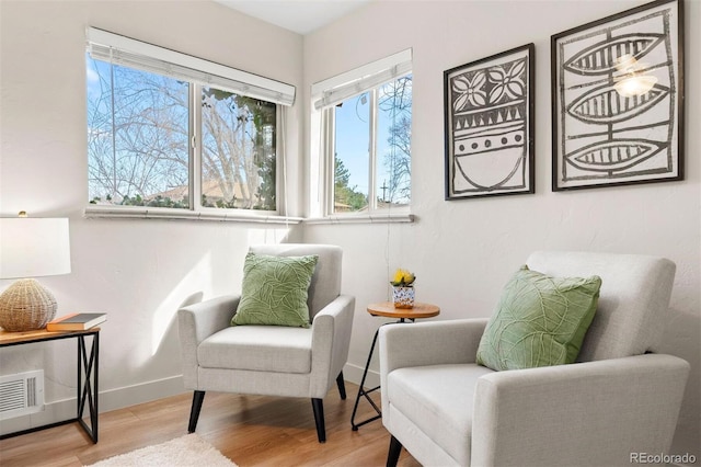 living area featuring visible vents, baseboards, and wood finished floors