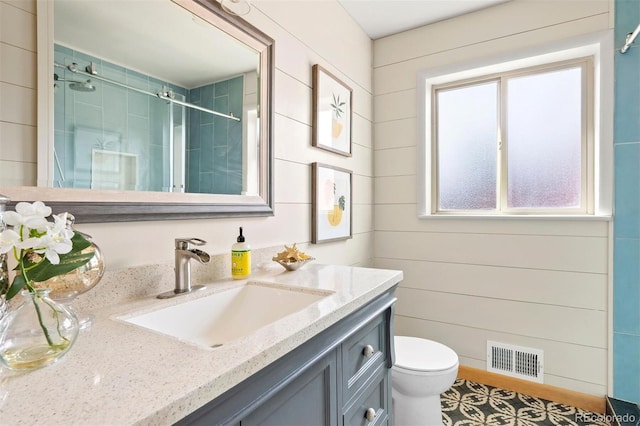 bathroom featuring vanity, toilet, visible vents, and a stall shower