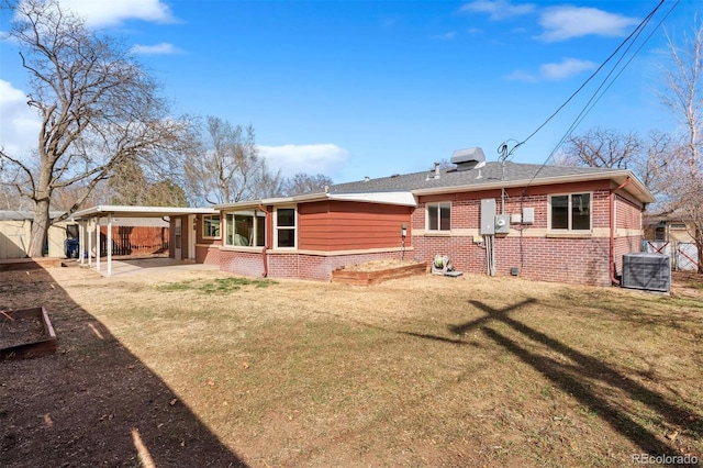 back of property with a lawn, driveway, fence, a carport, and brick siding