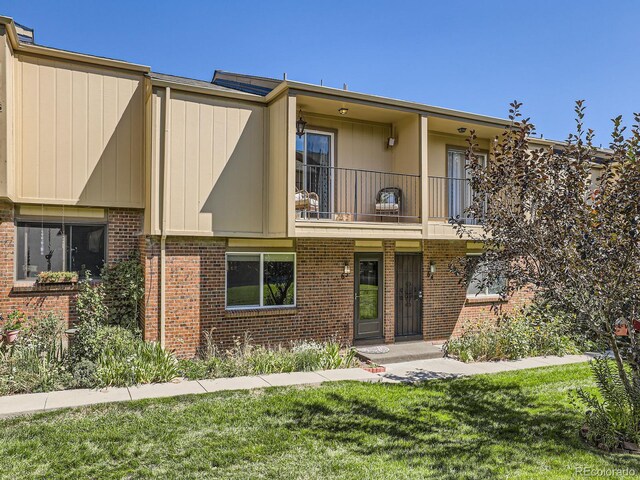 townhome / multi-family property featuring a balcony and a front yard