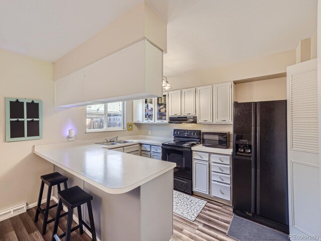 kitchen with white cabinetry, black appliances, kitchen peninsula, sink, and dark wood-type flooring