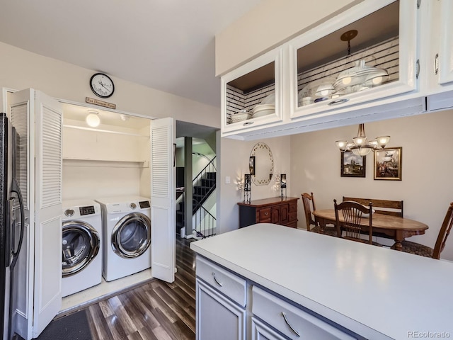 washroom with dark wood-type flooring, an inviting chandelier, and separate washer and dryer