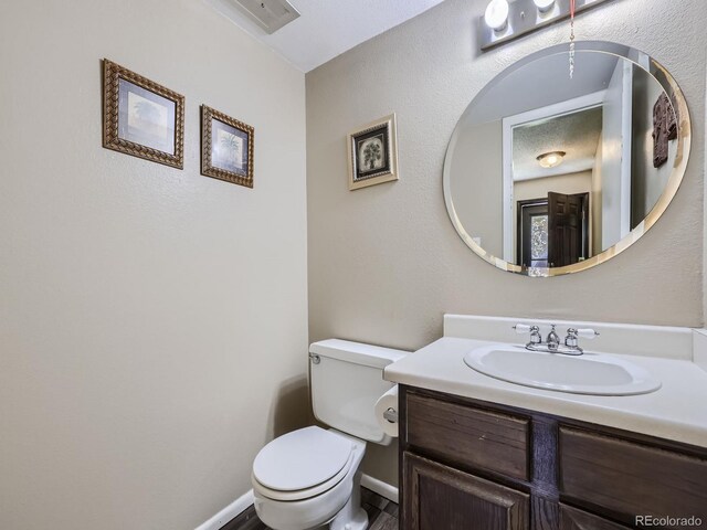 bathroom with a textured ceiling, vanity, and toilet