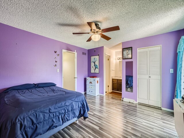 bedroom with hardwood / wood-style floors, a textured ceiling, ceiling fan, a closet, and ensuite bathroom