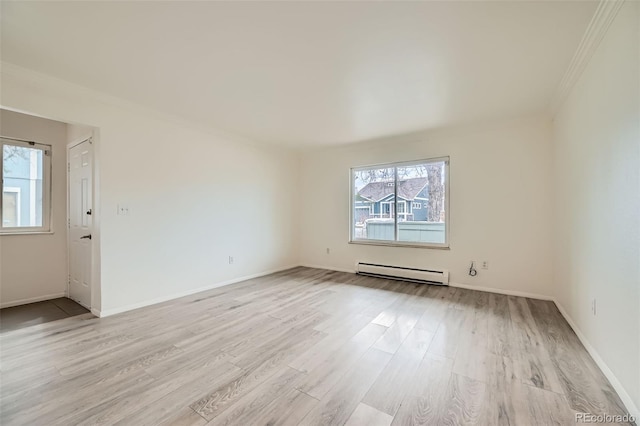 spare room featuring ornamental molding, light wood-style flooring, a baseboard heating unit, and baseboards