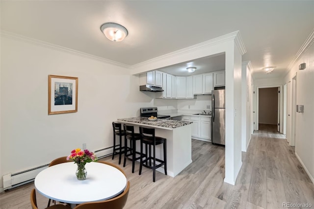 kitchen with a peninsula, appliances with stainless steel finishes, a sink, and a baseboard radiator