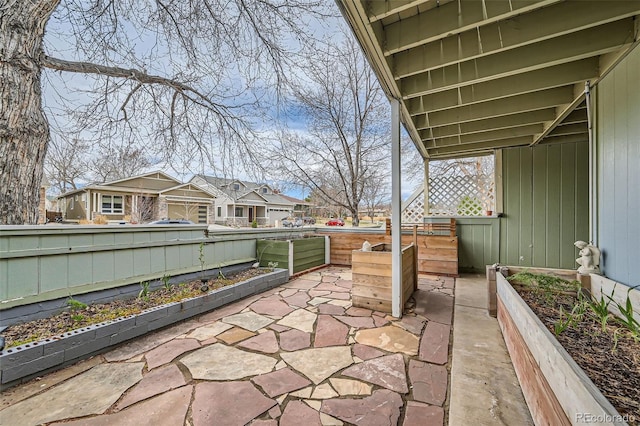 view of patio with fence, a residential view, and a vegetable garden