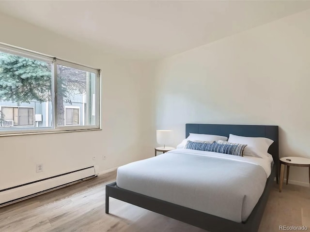 bedroom featuring baseboard heating, wood finished floors, and baseboards