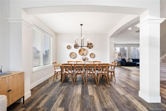 dining area featuring decorative columns, arched walkways, baseboards, dark wood-style flooring, and a chandelier