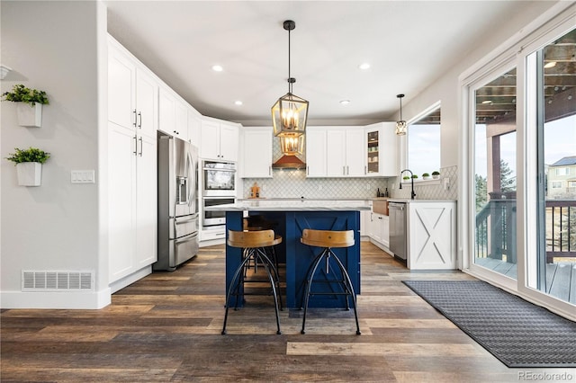 kitchen featuring tasteful backsplash, stainless steel appliances, light countertops, visible vents, and a kitchen island
