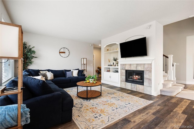 living room featuring stairway, wood finished floors, built in shelves, a fireplace, and baseboards