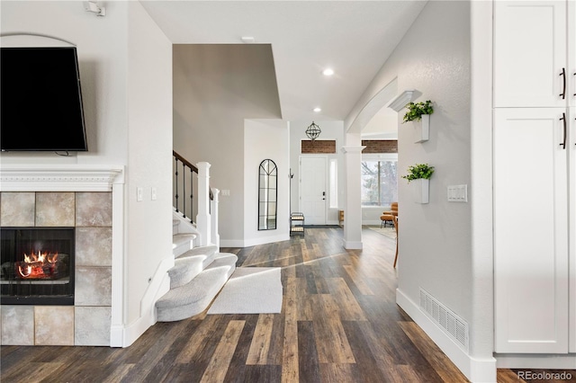 entryway featuring stairs, visible vents, baseboards, dark wood-style floors, and decorative columns