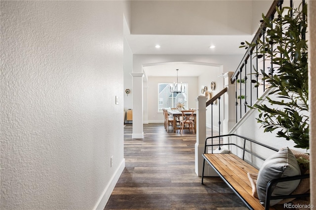 entrance foyer featuring a textured wall, arched walkways, baseboards, stairs, and dark wood-style flooring