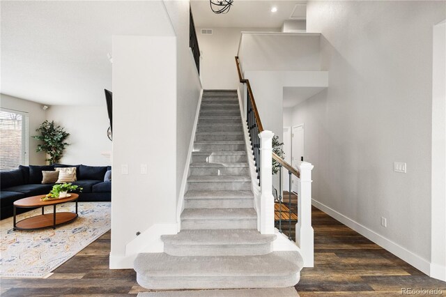 stairs with baseboards, wood finished floors, and visible vents