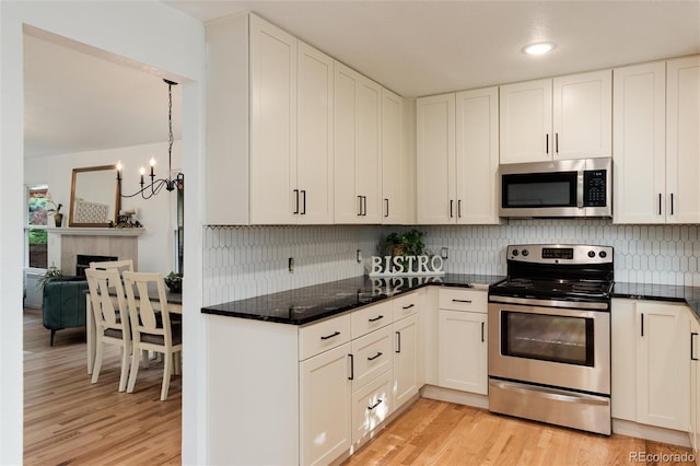8543 Redstone St, Highlands Ranch, CO 80126 - kitchen featuring stainless steel appliances, light wood-style floors, decorative backsplash, and a chandelier