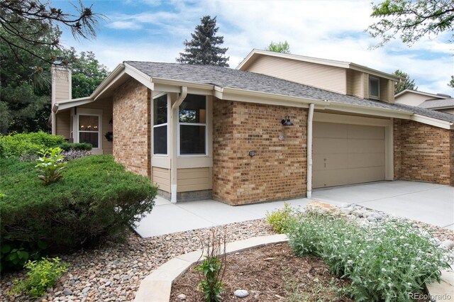 8543 Redstone St, Highlands Ranch, CO 80126 - view of front facade featuring driveway, brick siding, a garage, a chimney, and a shingled roof