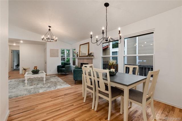 8543 Redstone St, Highlands Ranch, CO 80126 - dining space with a chandelier, light wood-style floors, lofted ceiling, and a tiled fireplace