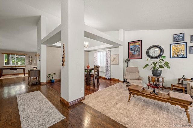 living area featuring lofted ceiling, baseboards, a chandelier, and wood finished floors