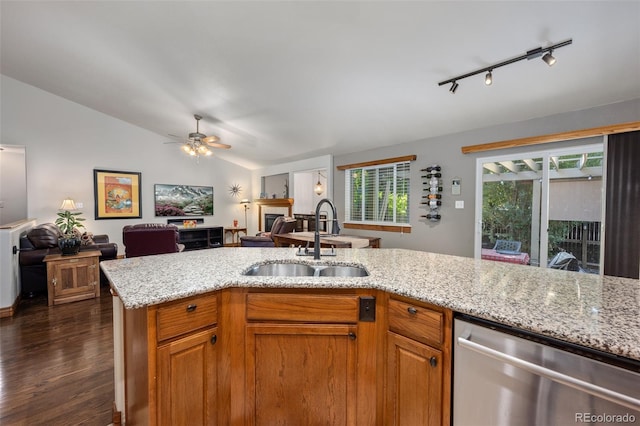 kitchen featuring a fireplace, a sink, vaulted ceiling, open floor plan, and dishwasher