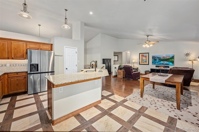 kitchen featuring stainless steel refrigerator with ice dispenser, sink, backsplash, hanging light fixtures, and ceiling fan